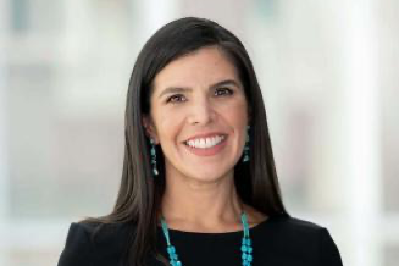 Smiling woman headshot wearing a black top with turquoise necklace and earrings