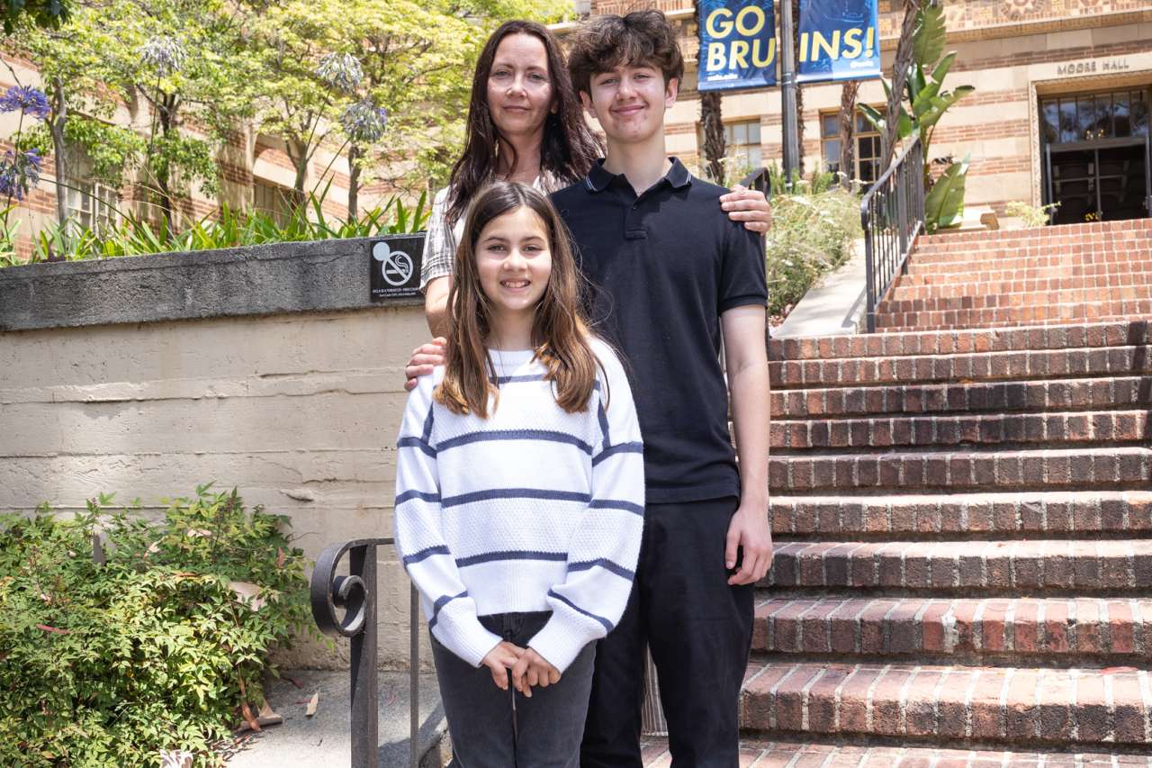 Luka poses with his mother and sister by the step of some brick stairs.
