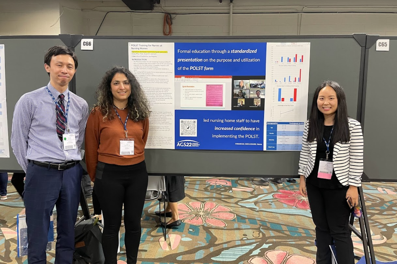 Three geriatric medicine fellows, stand in front of a poster at  a conference.