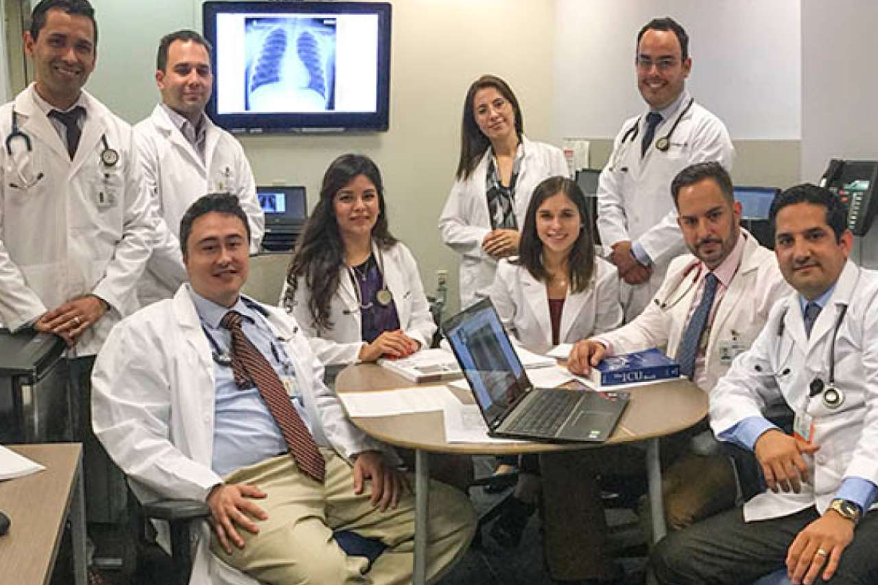 International Medical Graduate Program (IMG) Doctors siting on a rounded table wearing their white lab coats.