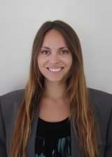 Smiling woman headshot with long brown hair wearing gray blazer