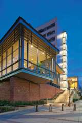 exterior of the UCLA Carnesale Commons building in the evening with lights on.