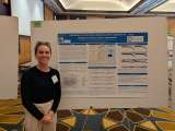 Ariel Hogan smiling at the camera as she stands by the display board for her project
