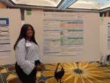 Phelan Glenn smiling at the camera as she stands by the display board for her project