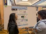 Jennifer Ann speaks with an interested person in front of the display board for her project