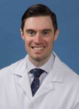 Head shot of John Thompson in white lab coat, smiling at camera