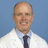 Head shot of Stanley Carmichael Jr wearing a white lab coat, smiling at the camera