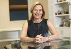 A person seated at a table, wearing a sleeveless black top and a necklace.