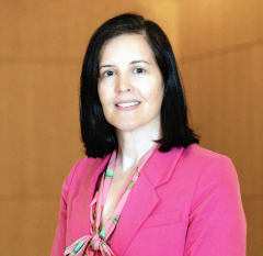 Jessica Phillips in a pink blazer with a floral top, standing indoors.