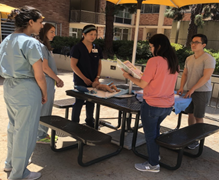 Five people around an outdoor picnic table reviewing paperwork