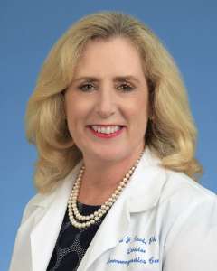 Dr. Elaine Reed in white coat with pearl necklace against blue background