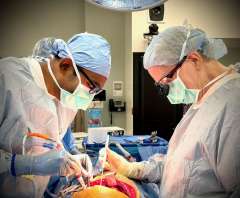Male and female UCLA doctors stand over a patient performing surgery