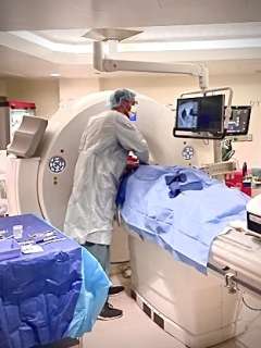 Dr. Fereidoun Abtin standing over a patient in a CT machine and performing CT guided biopsy