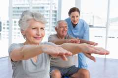 Older caucasian couple doing a stretching routine.