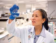 Dr. Linda Liau looking at a test tube.