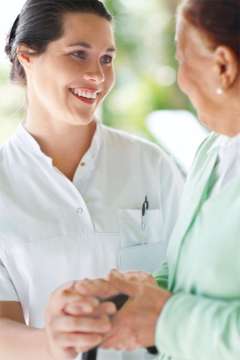 An employee holding the hand of an older patient