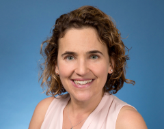 headshot of Joanna Shaenman in an indoor setting with a blue background