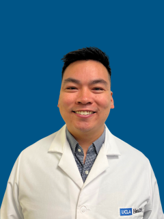 Person wearing white lab coat with UCLA Health logo on blue background