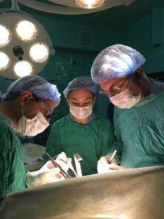 Three doctors operating on a patient