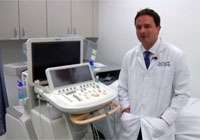 Dr Perens standing in front of machine