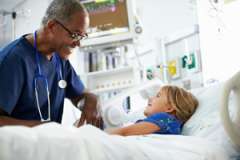 pediatrician talking to child in hospital bed