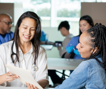 Healthcare professional smiling while discussing documents with a patient at a clinic
