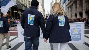 2 people holding hands with their backs to the camera, showing their Operation Mend jackets at the Veterans Day Parade in NYC