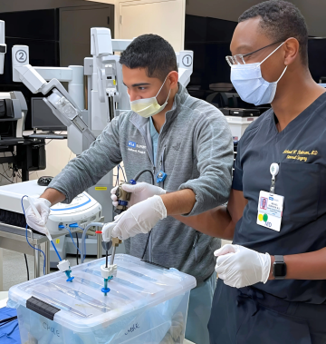 Two residents practice surgery on a simulator