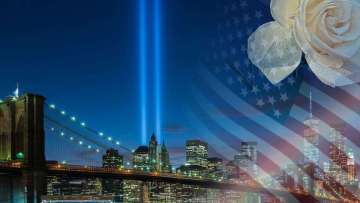 Brooklyn Bridge and New York skyline at night with twin blue beams and US flag overlay