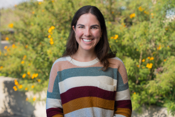 Tori Boyer, LCSW smiling, wearing a horizontal stripes colored sweater, and trees in the background.