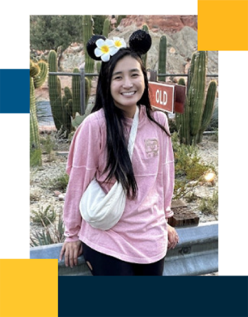 Kelly Cheung wearing a pink sweater, white fanny-pack, and Mickey Mouse ears.
