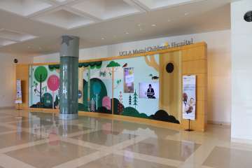 A wide shot of a brightly lit lobby with a colorful mural and signage reading "UCLA Mattel Children's Hospital."