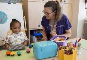 Teacher and a child counting toy cupcakes in a classroom