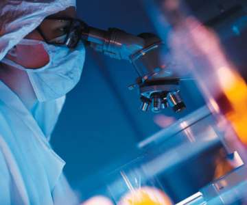 A researcher using a microscope to analyze a sample