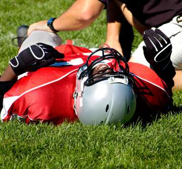 Injured American football player laying on a grass