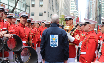 Operation Mend representative speaks with U.S. Marines in dress uniform during a city parade.