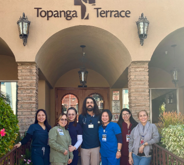 Eight people standing beneath Topanga Terrace entrance arch