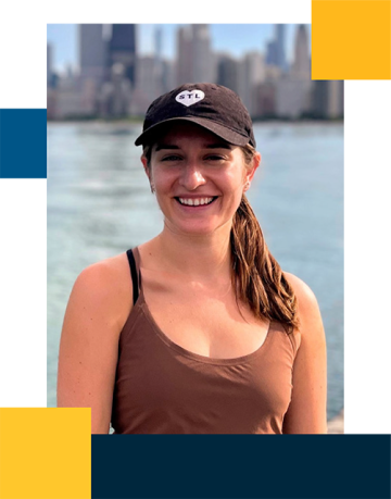 Laura Santangelo wearing a brown top and black hat with the bay and city in the background