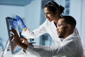 Male and female scientist looking at a computer together