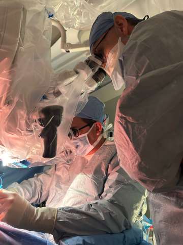 Two doctors stand over patient performing surgery in the OR