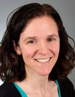 Smiling professional headshot of a woman with dark wavy hair