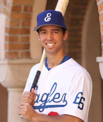 Adolescent male wearing baseball uniform holding bat
