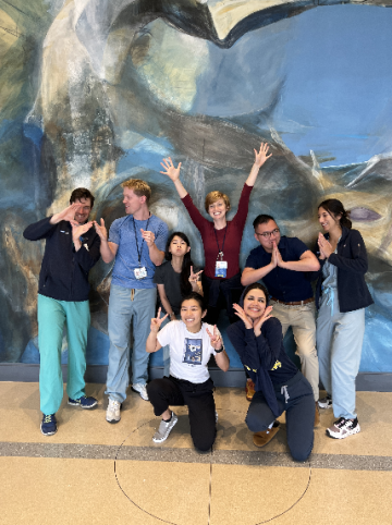 Eight UCLA Neurology Chief Residents posing happy for a picture in front of a painted mural