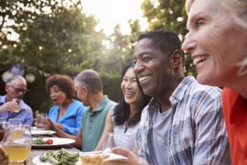 Friends sitting at a table smiling outside