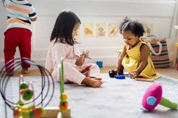 Two children playing with toys on the carpet