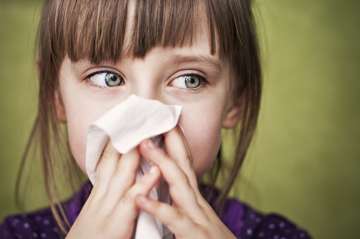 Girl blowing her nose with a tissue