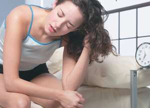 Tired woman sitting on bed