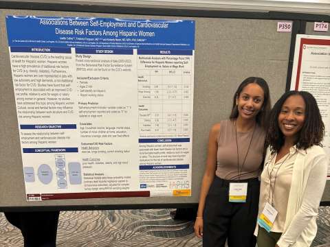 Lisette Collins and her mentor stand in front of her research poster on self‑employment and cardiovascular risk in Hispanic women