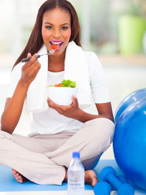 Woman on exercise mat eating fruit