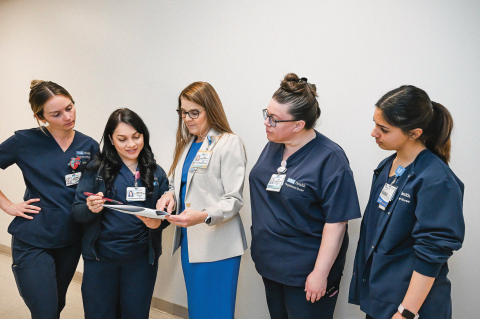 Three healthcare professionals discussing details with a document in hand.
